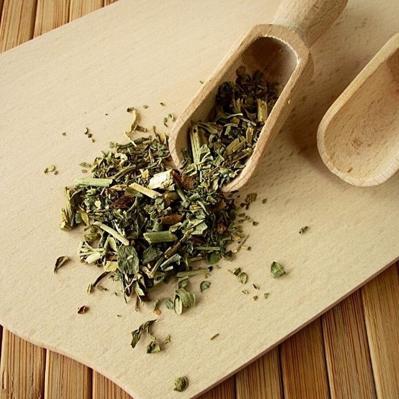 dried rue in a wooden spoon and on the table