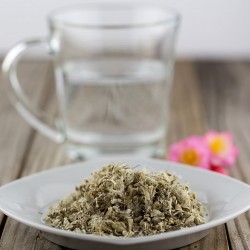 marshmallow root on a plate, next to a glass of water and a flower