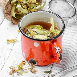 hojas de tilo y flores en una taza de té y una bolsa de tela