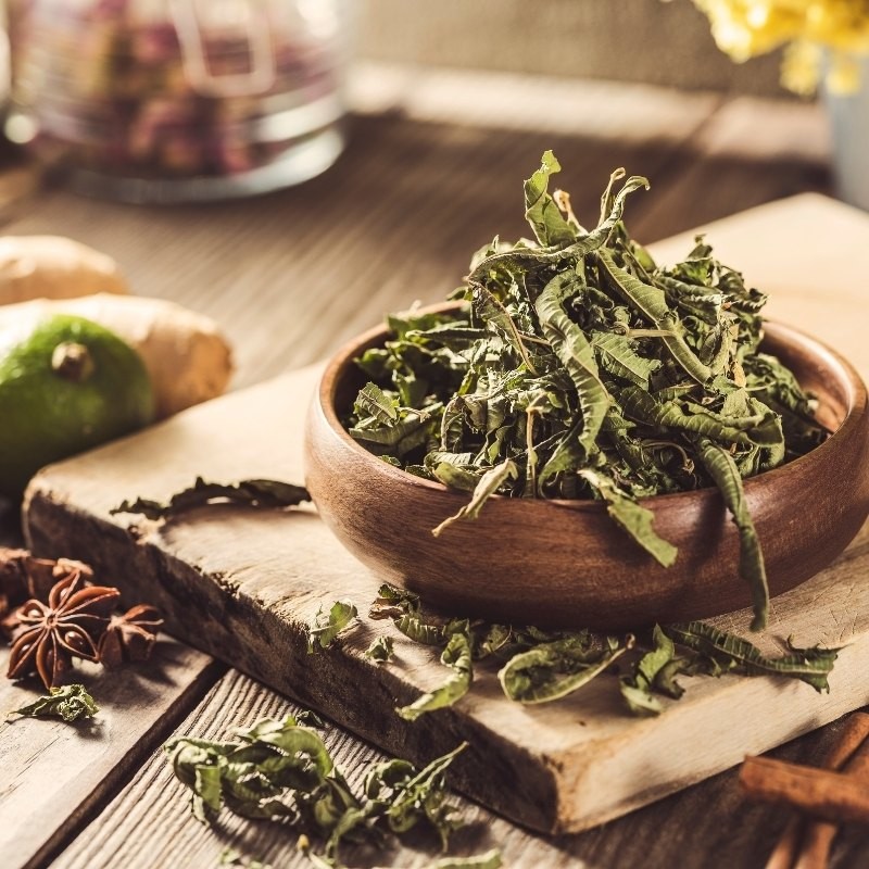 dried lemon balm leaves in a bowl on a table full of various spices