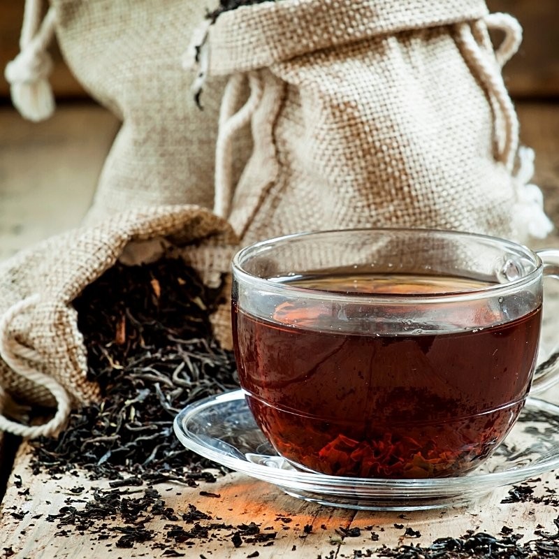 dried black tea in fabric bags next to a cup of tea