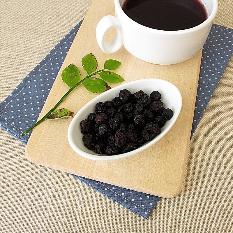 blackcurrant berries in a bowl next to a tea