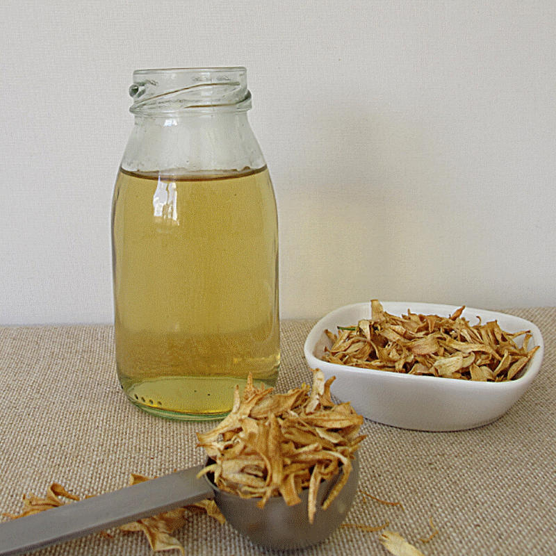 dried orange blossoms in a bowl and on the table, next to tea in a glass jar