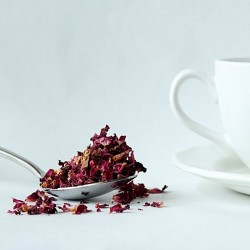 French rose petals on a spoon next to a cup