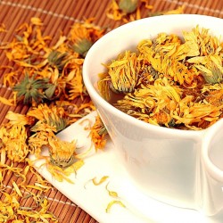 flores de caléndula en una taza y sobre la mesa.