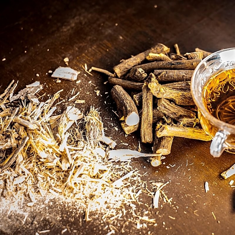 raíces de regaliz secas sobre la mesa y en forma de té