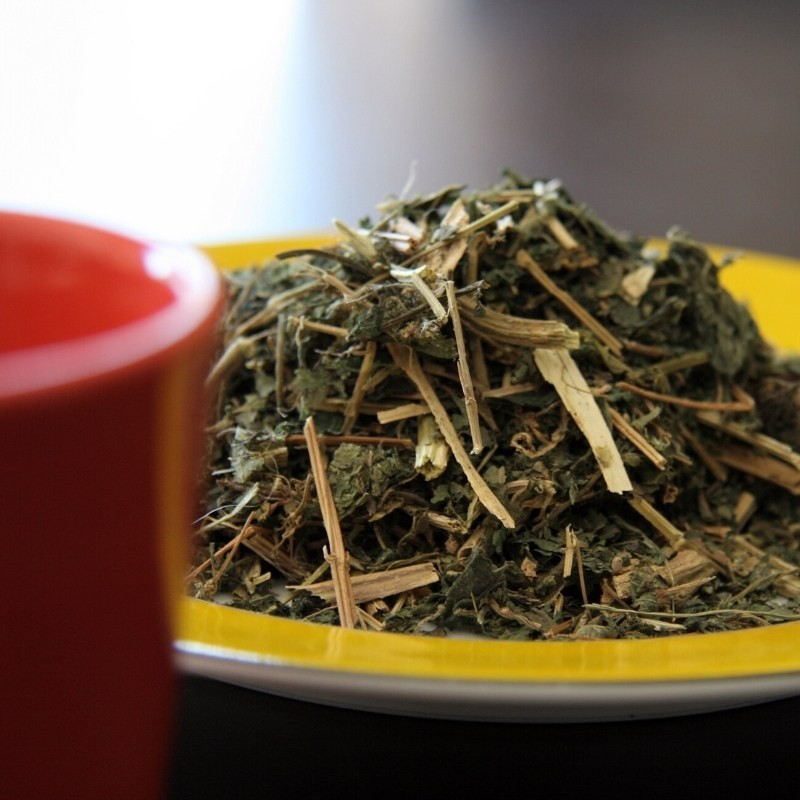 nettle leaves on a plate next to a cup